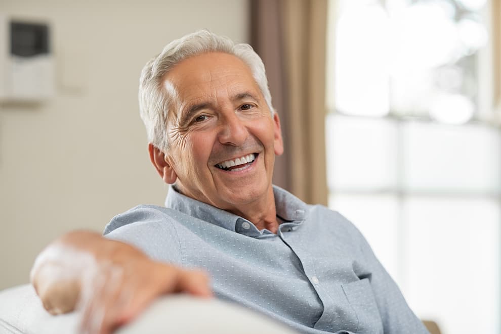 Older man sitting on a couch and smiling